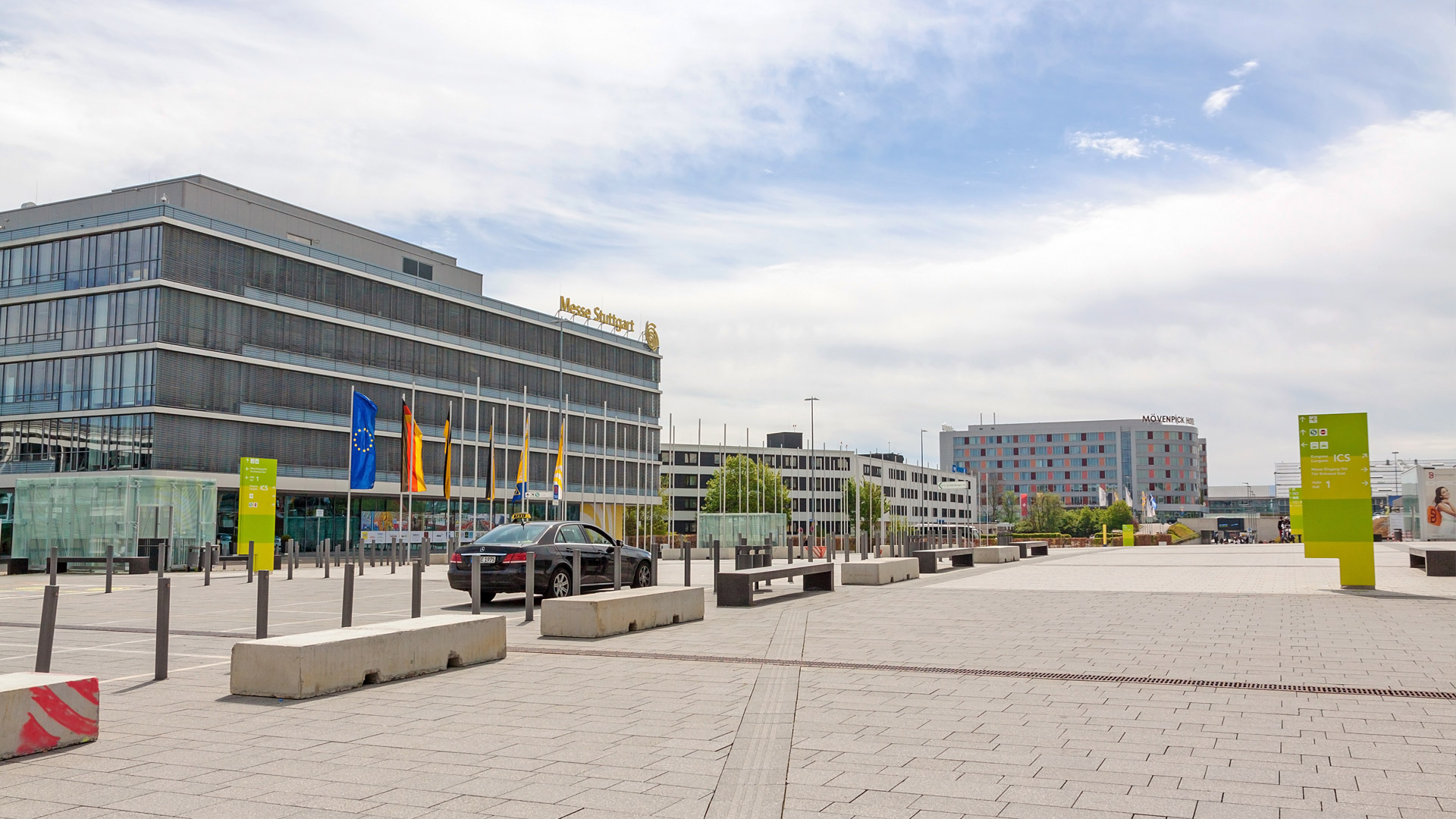 Panorama of the Stuttgart Exhibition Center with crowds of visitors on the outdoor grounds – modern entrance area and architecture in sunny weather