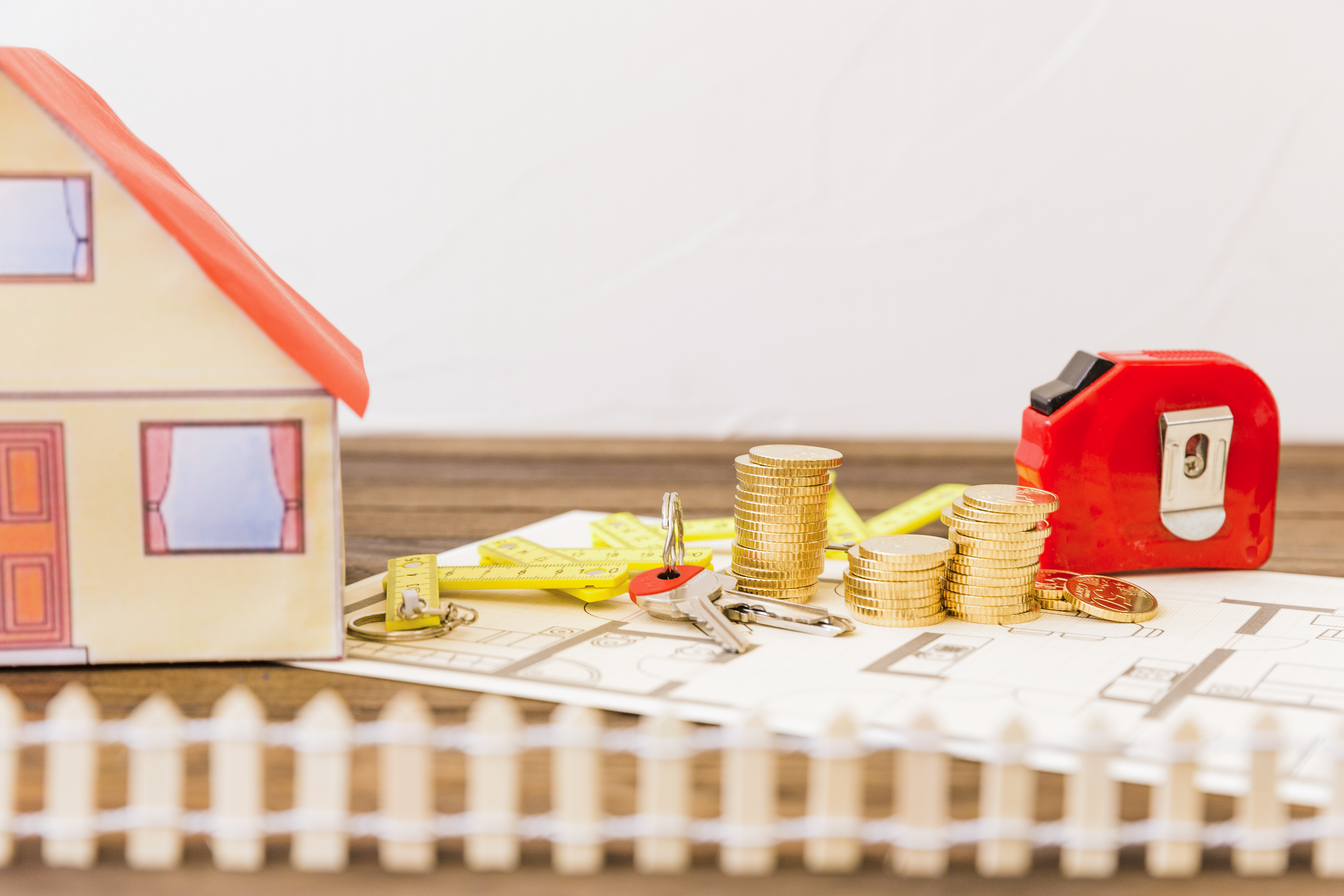 house besides measure tape stacked coins key blueprint